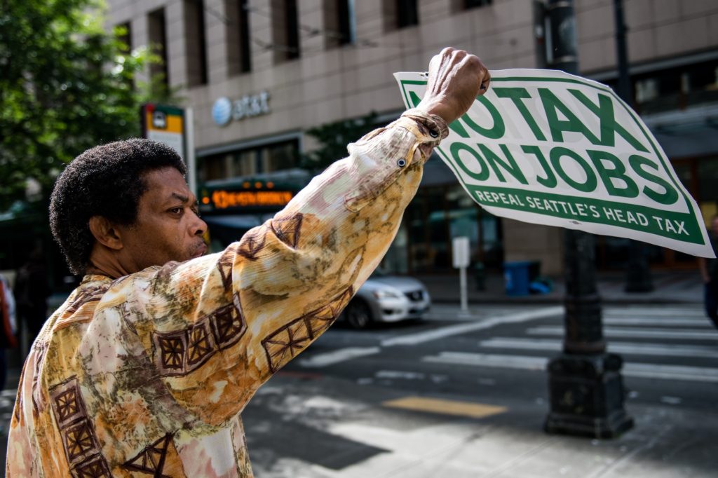 Man holding a sign calling for end of tax on jobs